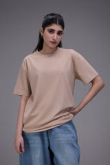 Woman wearing a beige t-shirt and blue jeans against a gray background