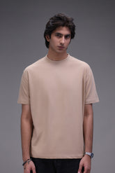 Man wearing a beige crew neck t-shirt in regular fit against a gray background
