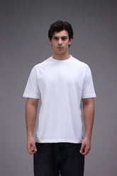 Man wearing a plain crew neck white t-shirt in regular fit against a gray background