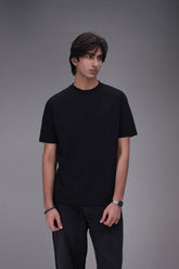 Person wearing a black Crew neck t-shirt regular fit and pants on a gray background