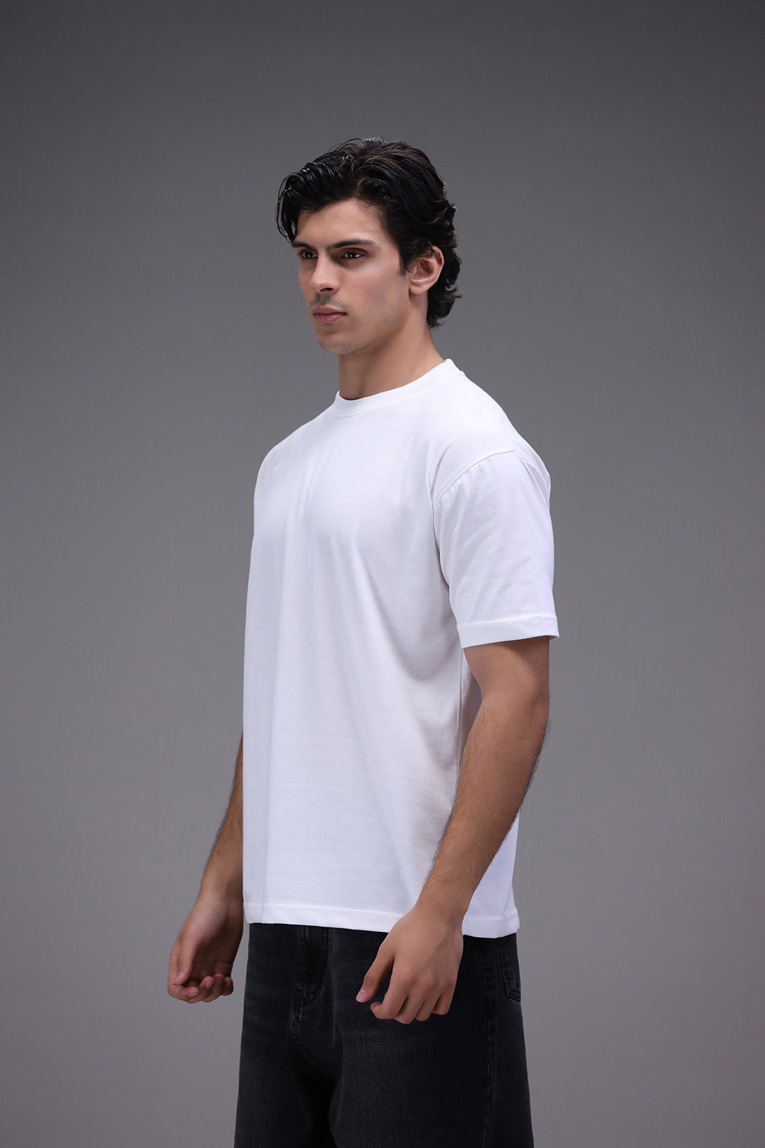 Man wearing a plain white t-shirt against a gray background