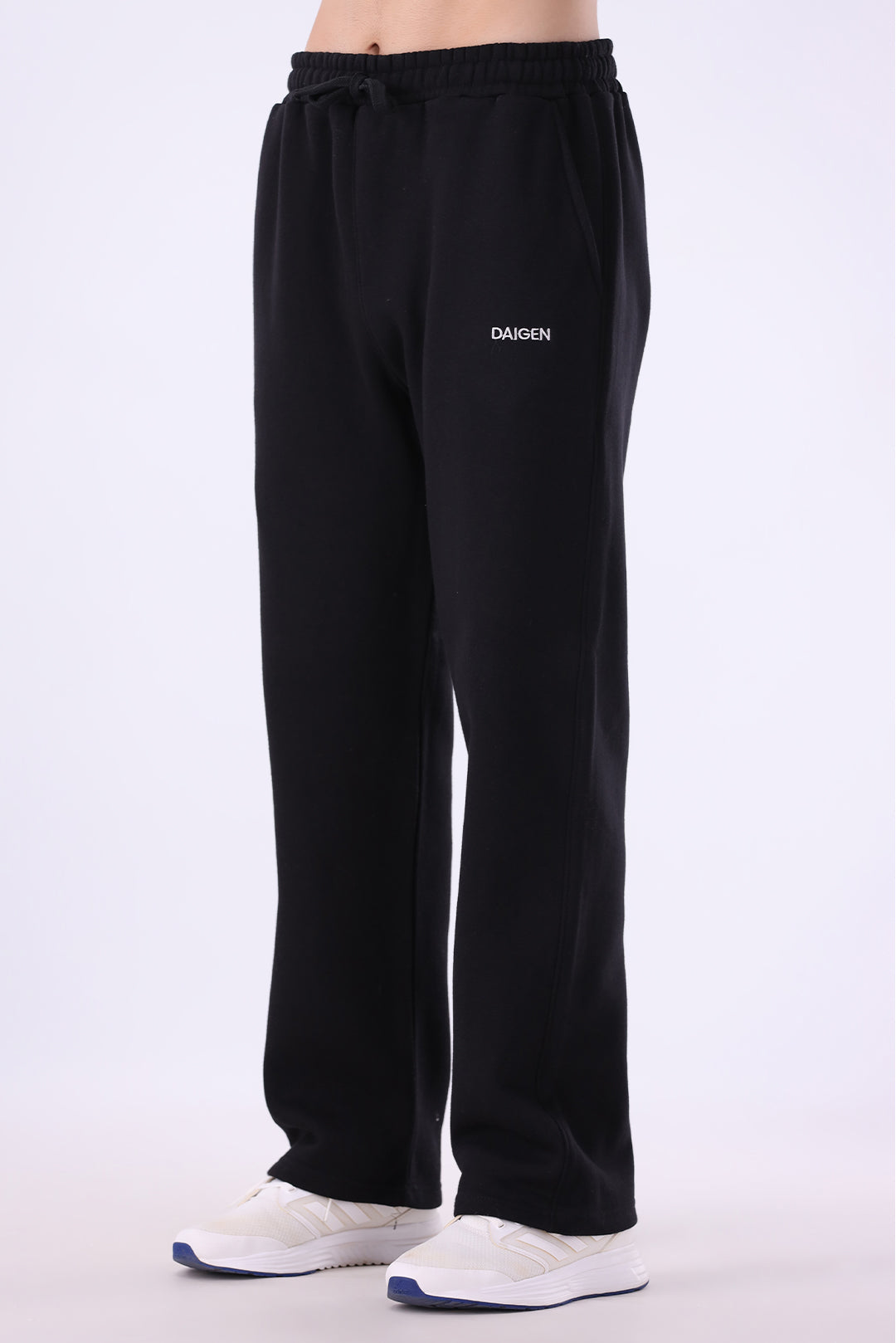 Black wide-leg sweatpants with a drawstring waist and white 'DAIGEN' branding on the left thigh, shown on a model wearing white sneakers against a light gray studio background.