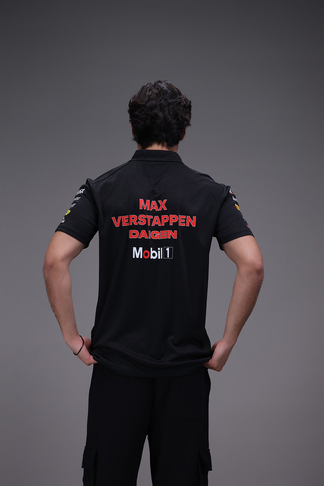 Person wearing a black shirt with 'Max Verstappen Daigen Mobil 1' branding on a gray background