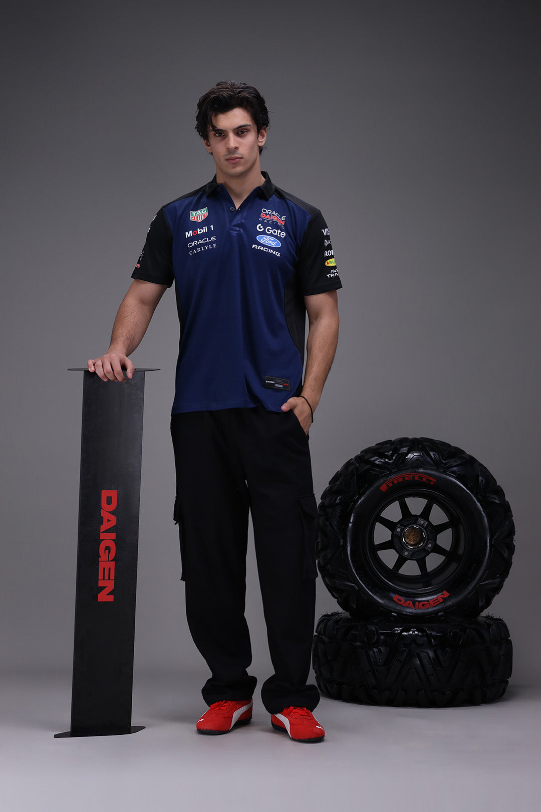 Person in Formula 1 Red bull racing uniform with tires and a Daigen product on a gray background