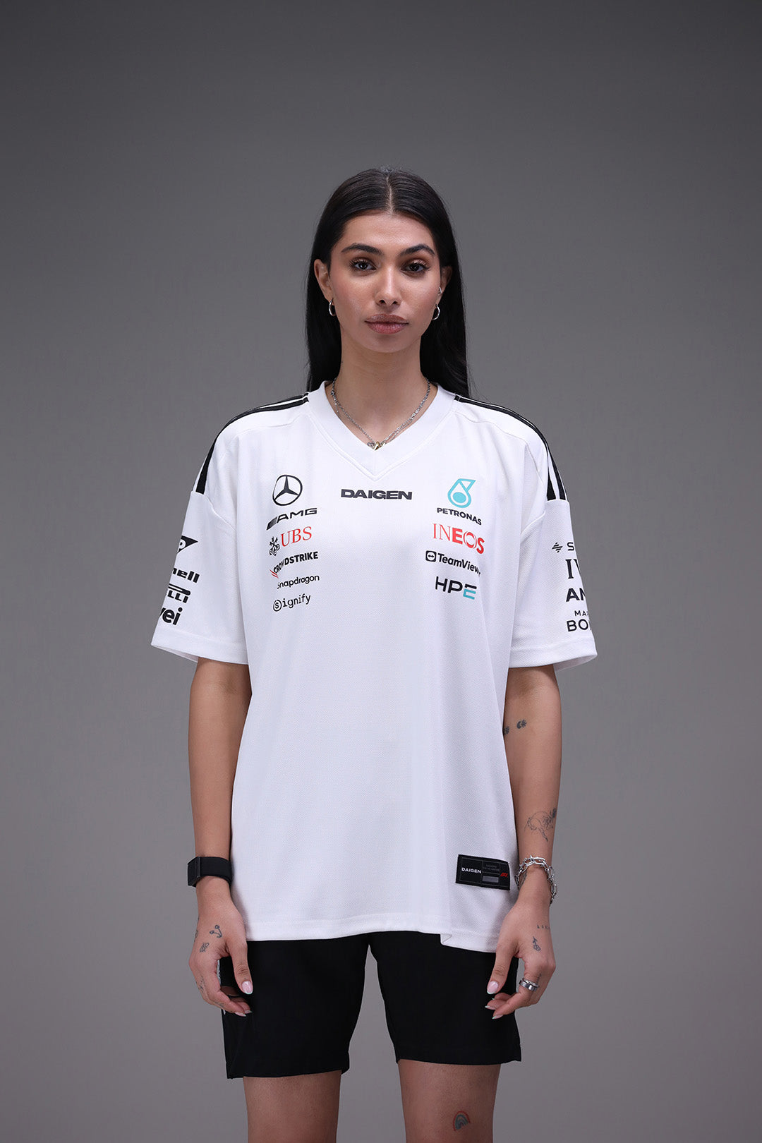 Person wearing a white mercedes amg petronas sports jersey with various sponsor logos on a gray background