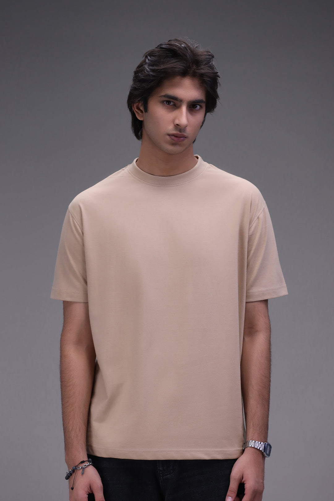 Man wearing a beige crew neck t-shirt in regular fit against a gray background
