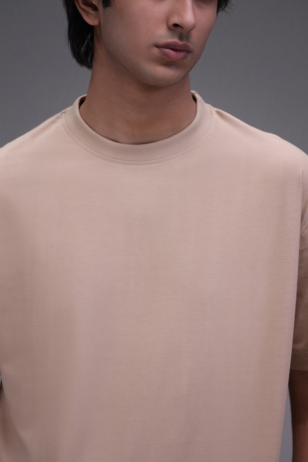 Man wearing a beige t-shirt showing fit fabric and detailling