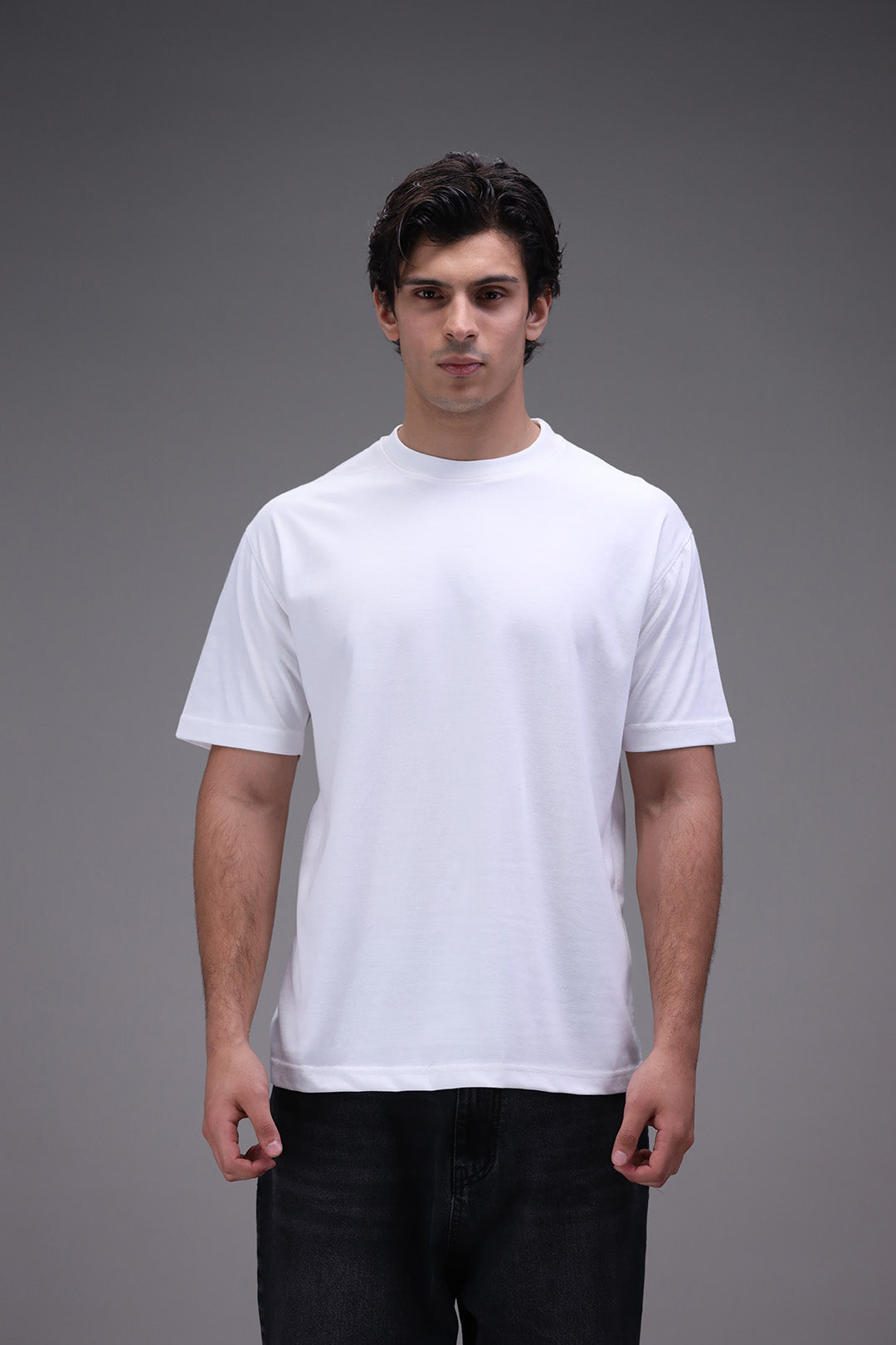 Man wearing a plain crew neck white t-shirt in regular fit against a gray background