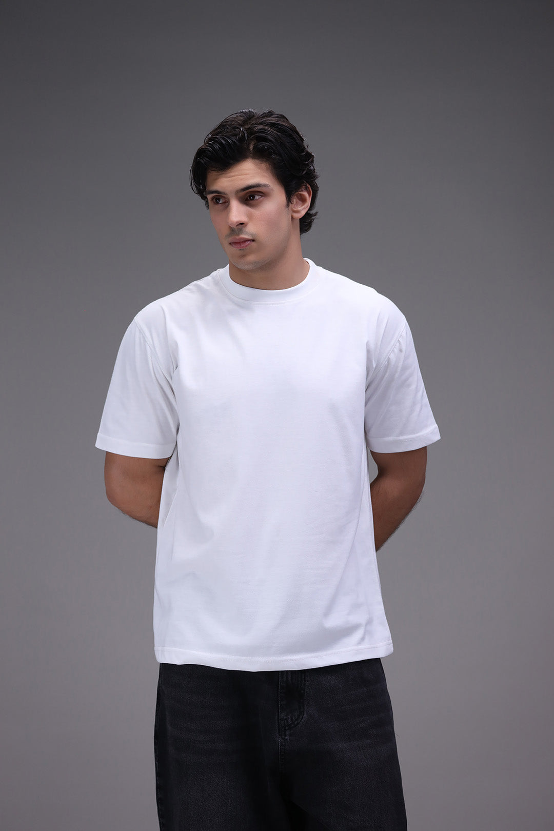 Man wearing a plain white t-shirt against a gray background