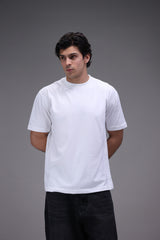Man wearing a plain white t-shirt against a gray background