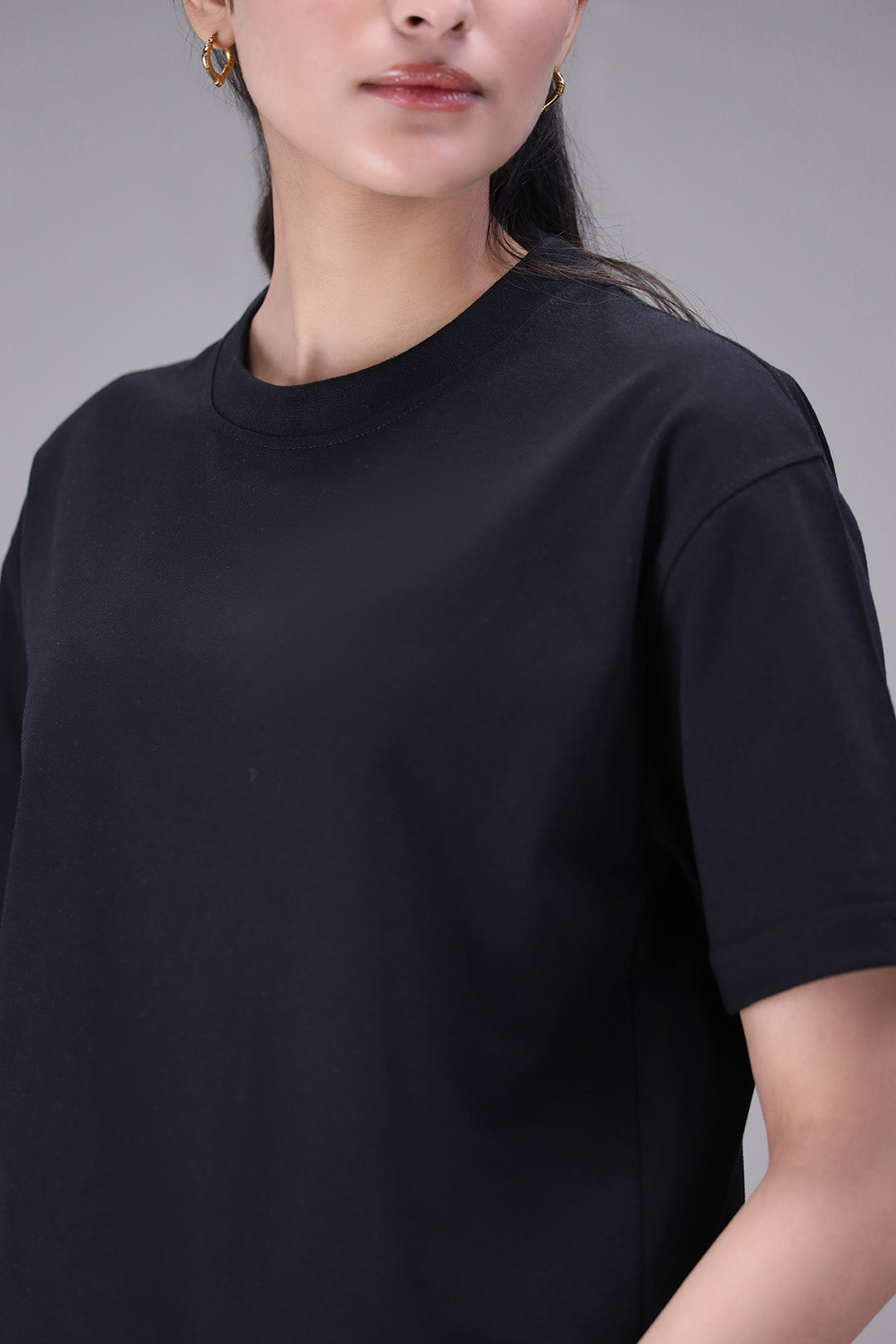 Person wearing a black t-shirt against a gray background