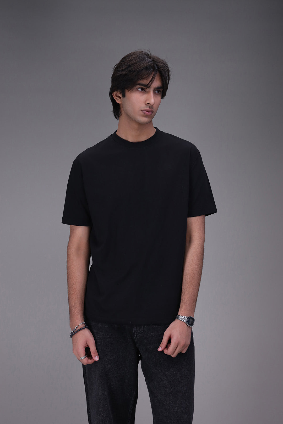 Person wearing a black Crew neck t-shirt regular fit and pants on a gray background