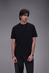Person wearing a black Crew neck t-shirt regular fit and pants on a gray background