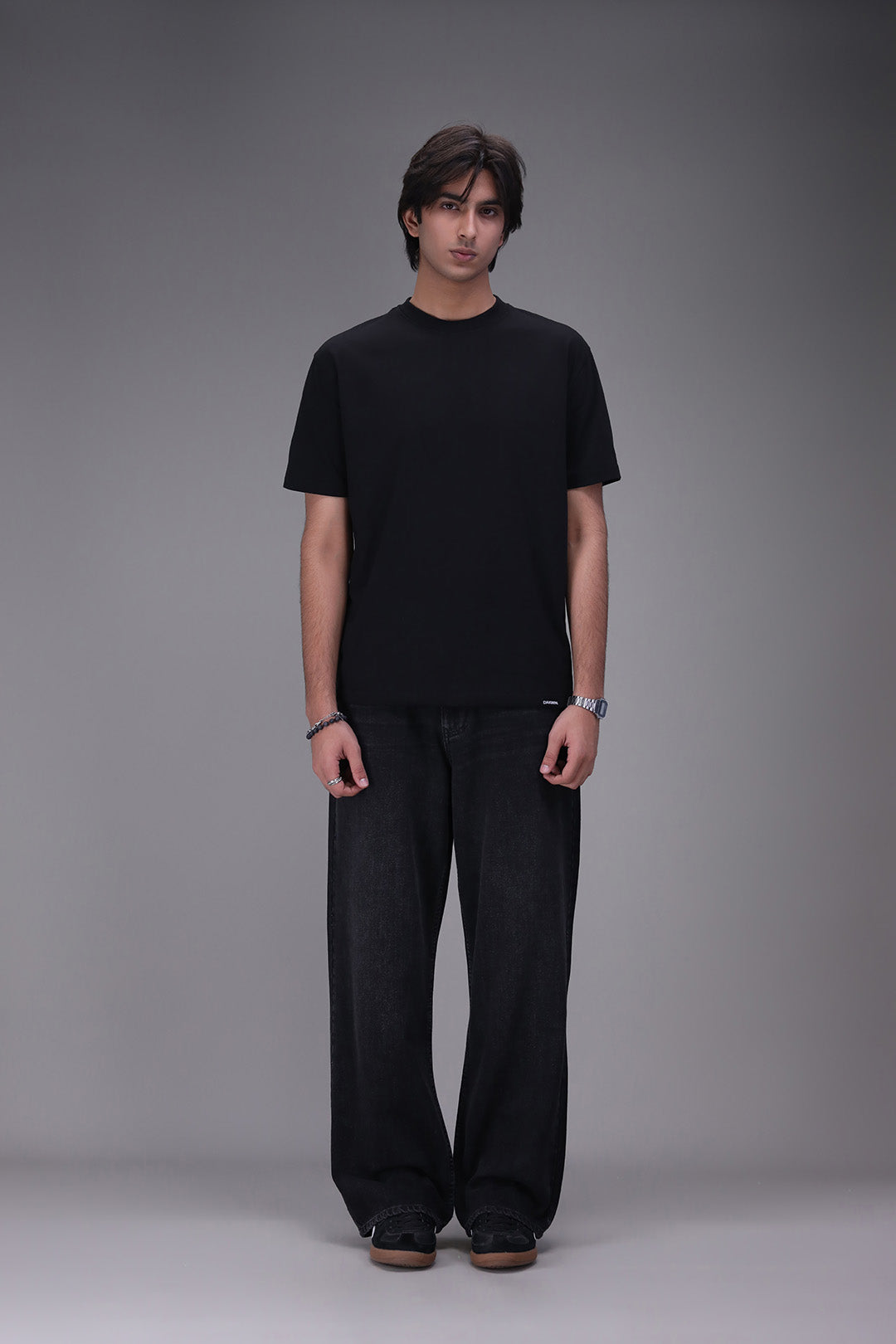 Person wearing a black t-shirt and black pants on a gray background