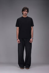 Person wearing a black t-shirt and black pants on a gray background
