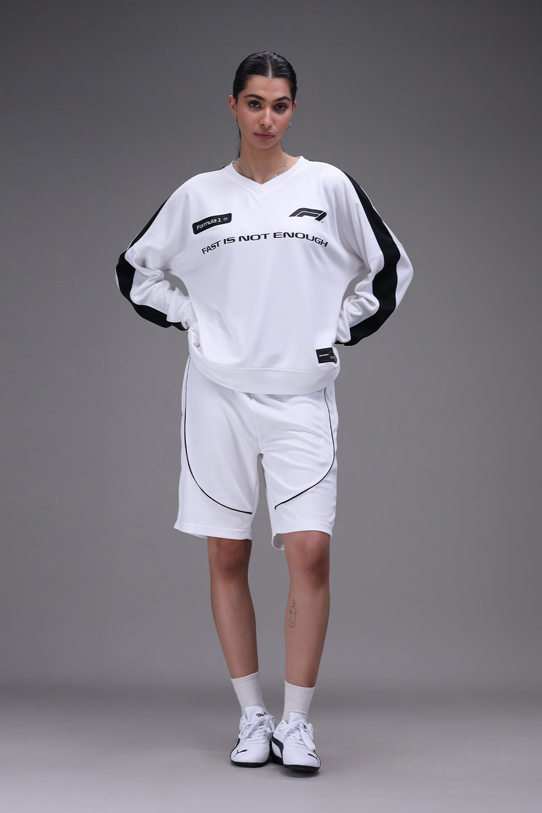 Person wearing a white formula 1 jersey outfit with black accents on a gray background