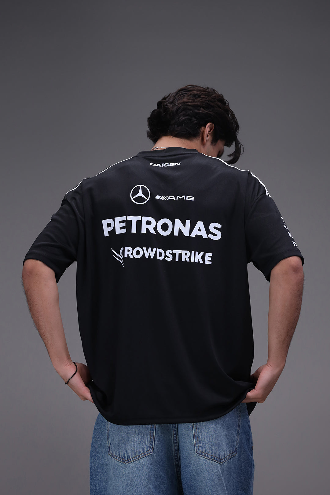 Person wearing a black jersey with Mercedes-Benz and Petronas logos on a gray background