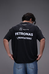 Person wearing a black jersey with Mercedes-Benz and Petronas logos on a gray background