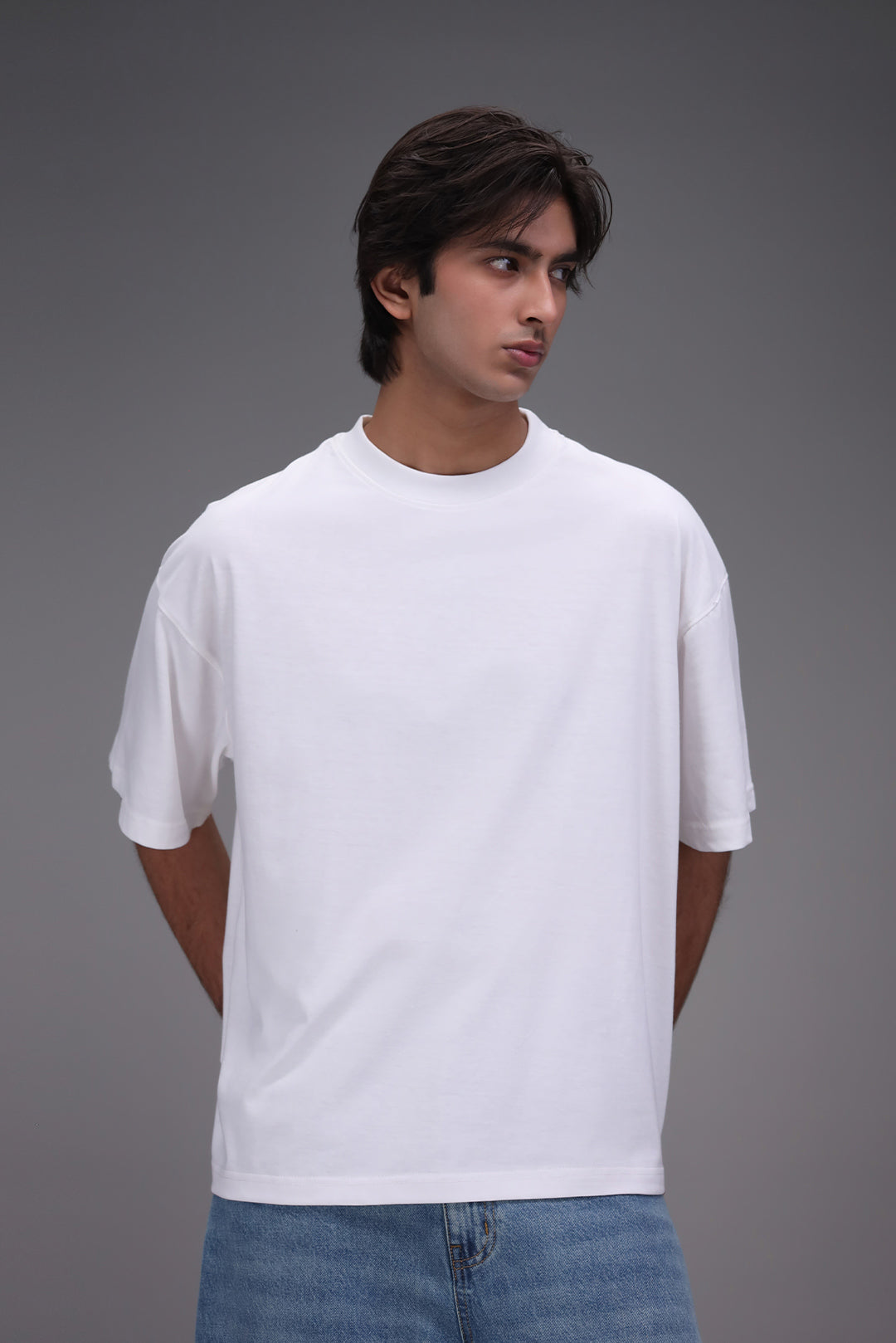 Man wearing a plain white oversized t-shirt and blue jeans for streetwear fast fashion trend